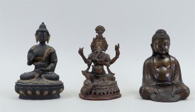 trois statues de Bouddha en bronze, assises sur un socle blanc