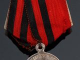 an old medal with a red ribbon and a silver medal on a black surface