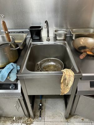 stainless steel kitchen sink with pots and pans on top of it