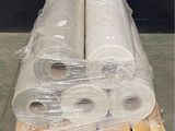 Plusieurs rouleaux de plastique sont empilés sur une palette dans un entrepôt