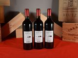 three bottles of red wine sitting on a table next to a wooden box