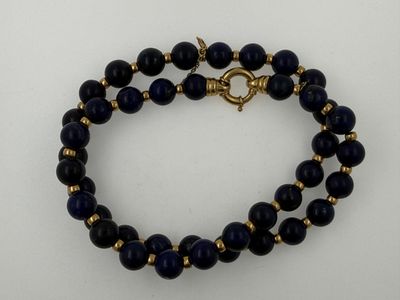 a close up of a blue beaded bracelet on a white surface