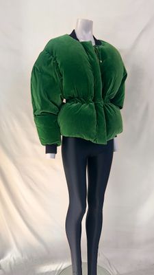 veste en velours vert sur un socle de mannequin, avec un legging noir
