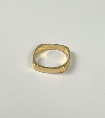 gros plan d'une bague en or sur une surface blanche