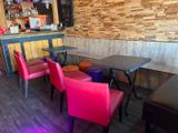 des chaises et des tables aux couleurs vives dans un restaurant, avec un bar en arrière-plan