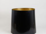 a black vase with a gold rim sits on a white surface