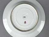 underside view of a white plate with a gold rim on a gray surface