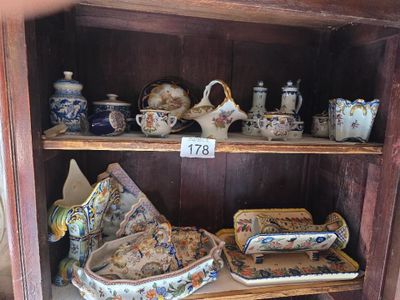 une étagère en bois sur laquelle sont disposées de nombreuses pièces de poterie de styles variés