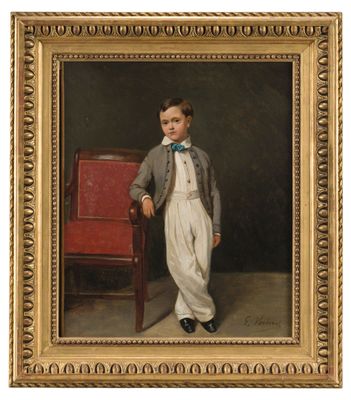 portrait of a young boy in a suit and bow tie standing next to a red chair
