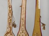 trois cuillères en bois ornées de motifs dorés et rouges et munies de pompons
