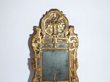un petit miroir avec un cadre doré posé sur une surface blanche