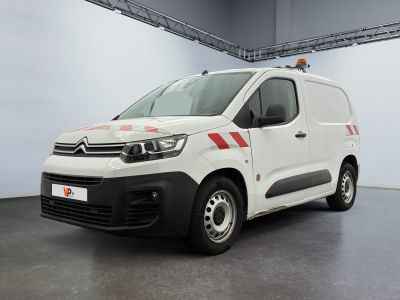 La camionnette blanche est garée dans un garage et présente une bande rouge sur le côté.