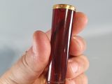 a hand holding a lighter that is red and gold
