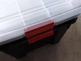 a plastic box with a red handle on the floor