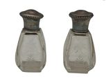 deux salières et poivrières en verre sur un fond blanc