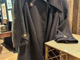 manteau en laine exposé dans un magasin, avec une chaise en arrière-plan