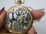 a person holding a gold pocket watch in their hand