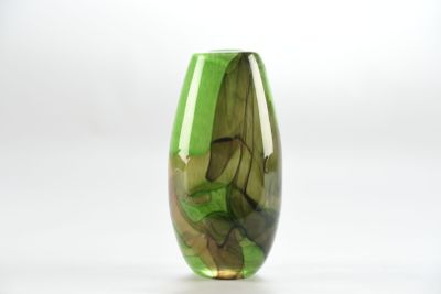 un vase en verre vert contenant des feuilles, posé sur une surface blanche