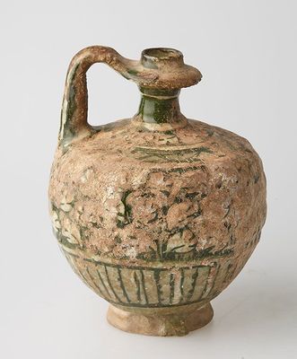 un petit vase muni d'une anse, posé sur une surface blanche