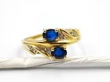 un gros plan d'une bague en or sertie de deux pierres bleues