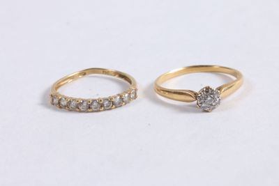 two gold rings with diamonds on them on a white surface