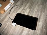 a black stove top sitting on the floor next to a box