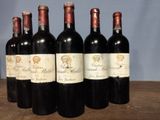six bottles of red wine are lined up on a wooden table