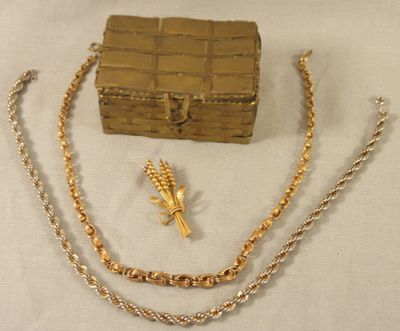 un collier en or, un bracelet et un coffret posés sur une table
