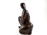 a statue of a person sitting on a white surface