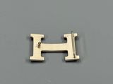 a close up of a metal letter h on a gray surface