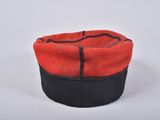 a close up of a red and black hat on a white surface
