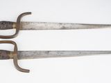une paire d'épées anciennes et usées posées sur une surface blanche