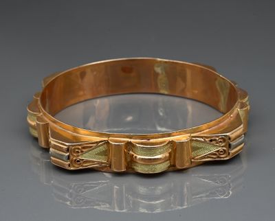 a close up of a gold bracelet on a reflective surface