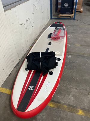 une planche de surf rouge et blanche sur laquelle est posé un sac noir