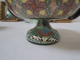 a colorful bowl sitting on a table with a picture on the wall behind it