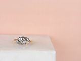 un gros plan d'une bague de fiançailles en diamant posée sur un bloc de marbre blanc