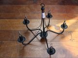 un lustre noir à cinq lumières posé sur un parquet