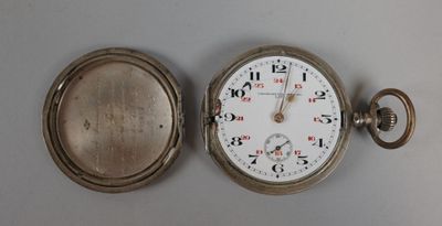 une montre de poche en argent posée sur une table à côté d'une horloge