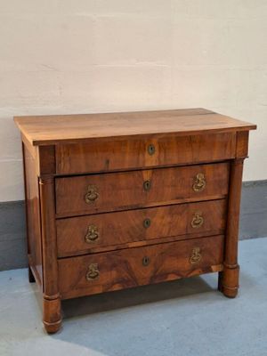 a small wooden chest of drawers in a room