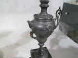 un vase en argent posé sur un socle, sur une table