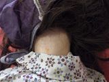 a close up of a doll ' s head with a purple hat on