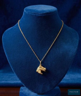 a gold necklace with a dog ' s head on a mannequin