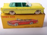yellow and red toy car sitting on top of a box on a white surface