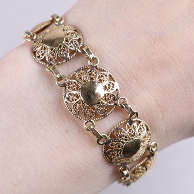 an image of a close up of a person ' s arm wearing a gold bracelet