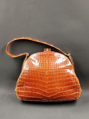 un sac à main en cuir de crocodile orange sur fond gris