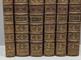 six vieux livres sont alignés sur une surface blanche