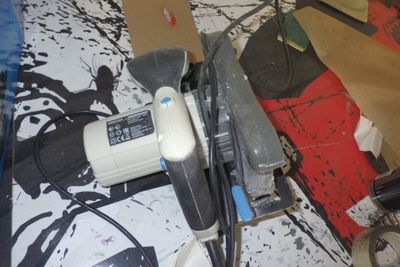 Quelqu'un utilise une ponceuse pour poncer une feuille de papier.