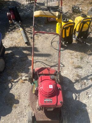 a red lawn mower sitting on the ground next to other lawn mowers