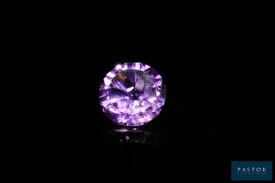 a close up of a purple diamond on a black surface