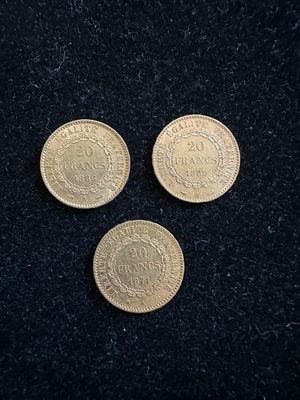 On voit trois pièces d'or sur une surface noire